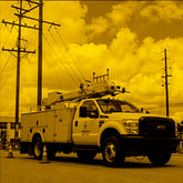 Utility truck with equipment on a street against a cloudy sky.